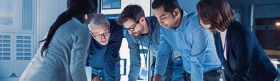 Engineers Meeting in Technology Research Laboratory: Engineers, Scientists and Developers Gathered Around Illuminated Conference Table, Talking and Finding Solution, Inspecting and Analysing Industrial Engine Design.